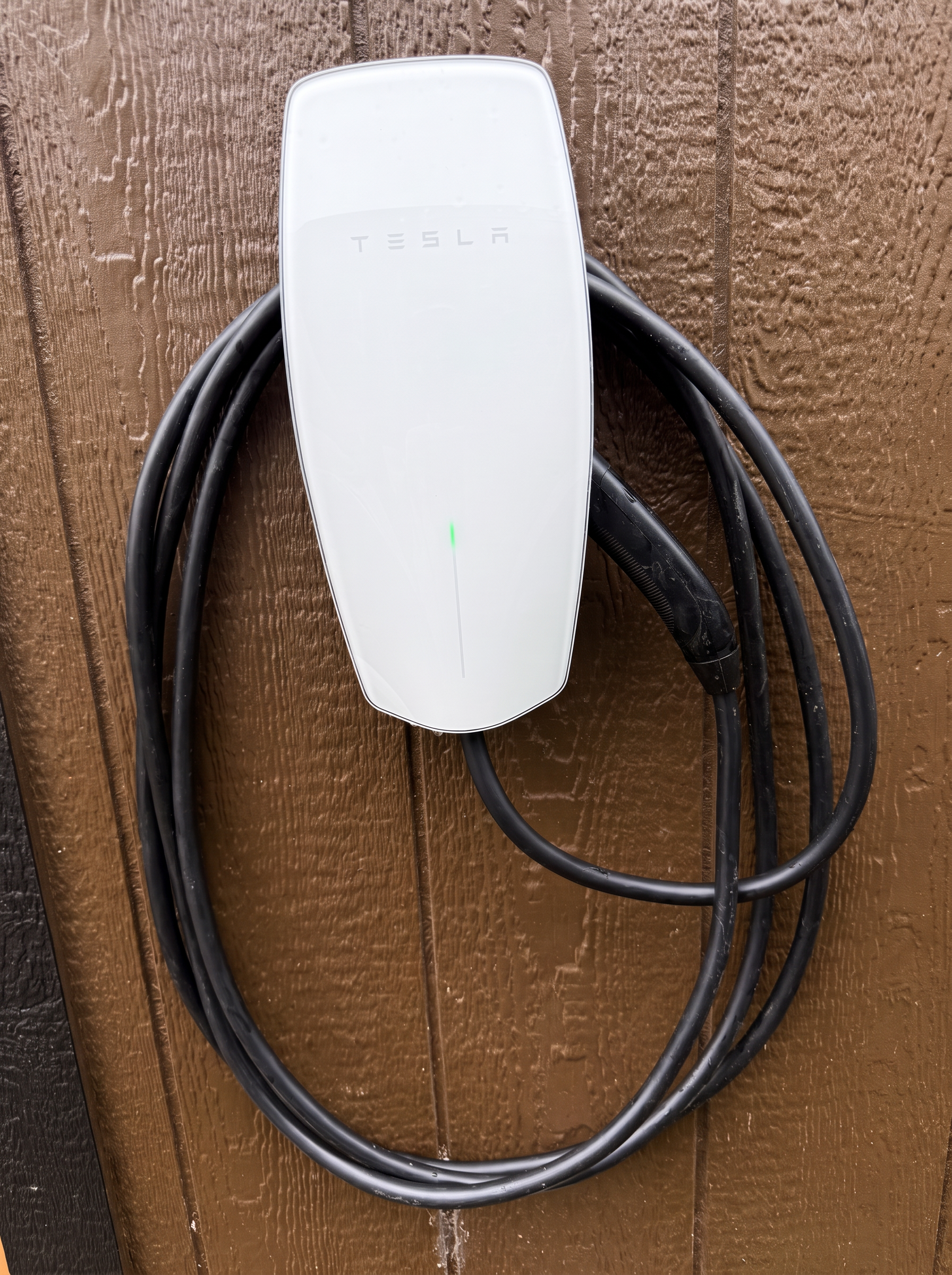 Close-up of a Tesla wall connector with coiled charging cable